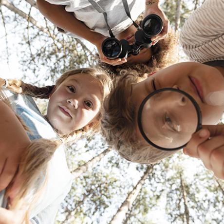 Des enfants avec une loupe et un parchemin font un jeu de piste