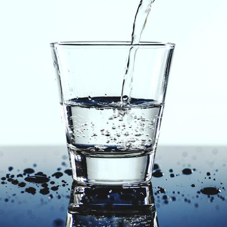 Verre d'eau Un verre d'eau transparent sur une table avec quelques gouttes